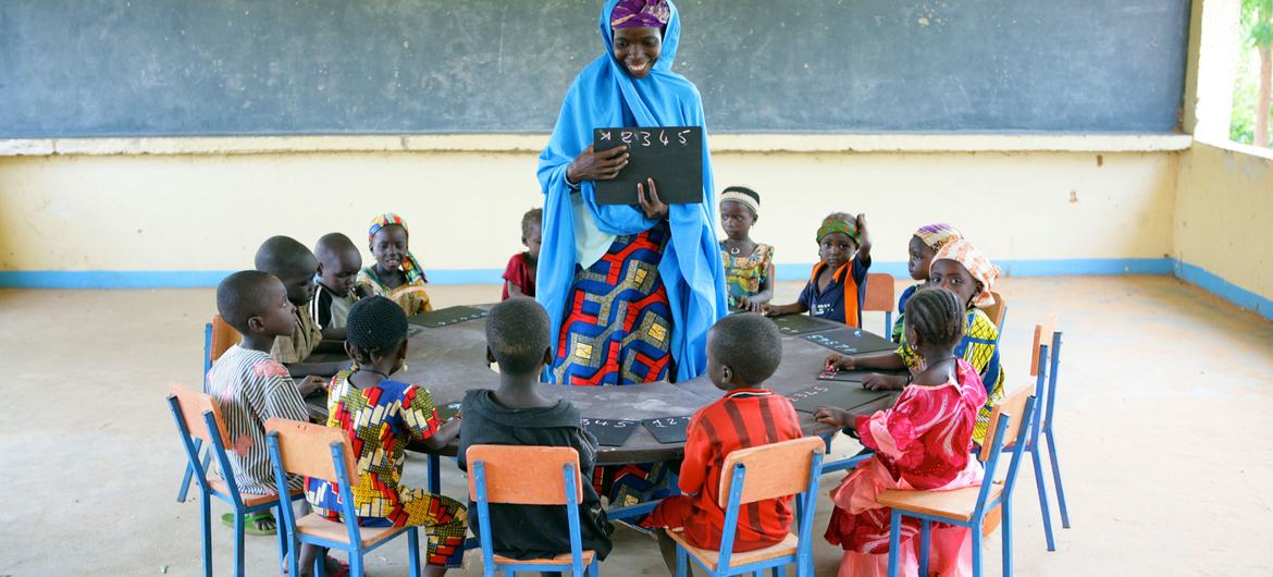 کودکان با معلم خود در مرکز رشد کودک در روستای گارین باجینی، در جنوب شرقی نیجریه به صورت دایره ای می نشینند.